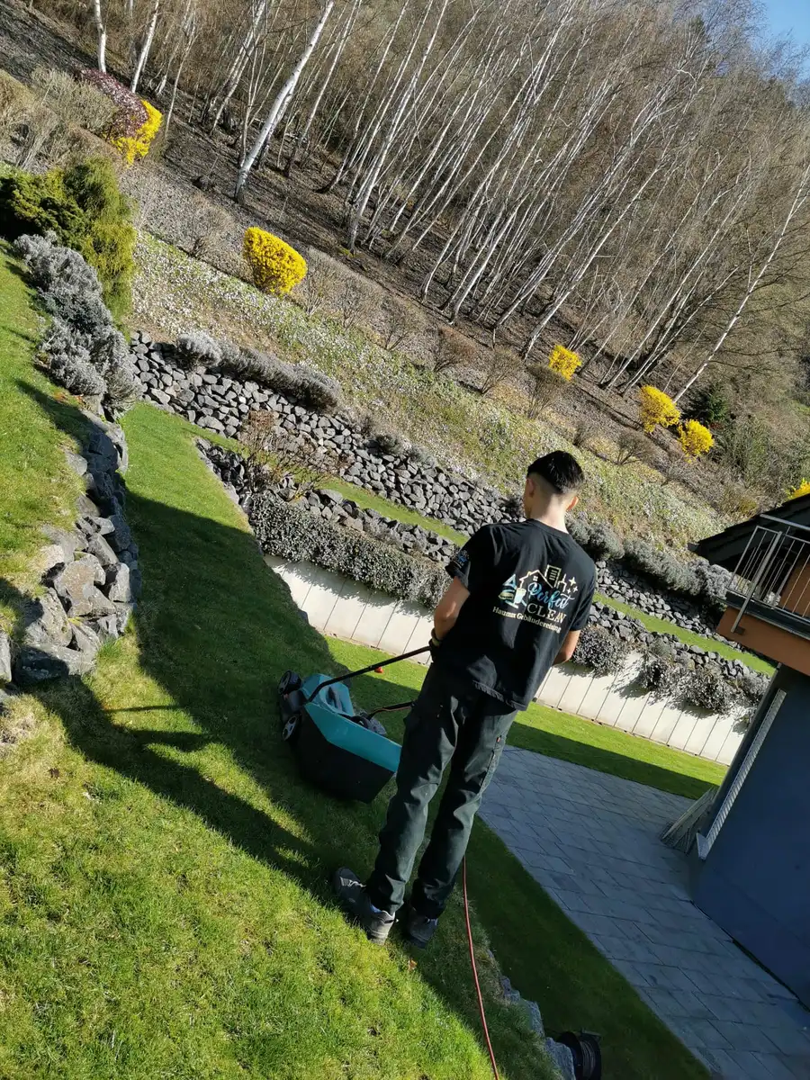 Mitarbeiter von Haumax beim Rasenmähen auf einem Hanggrundstück